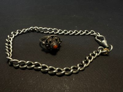 a close up of a silver chain with a red bead on it