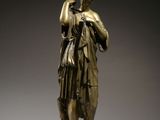 bronze statue of a woman holding a bird on a pedestal