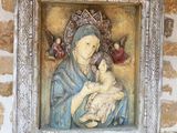 tableau représentant une femme tenant un bébé dans ses bras, encadré et accroché à un mur de pierre
