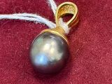 a picture of a black pearl pendant on a red cloth