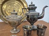 silver cups and a teapot sitting on a table