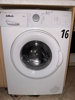 une machine à laver blanche posée dans une cuisine, à côté d'un plan de travail