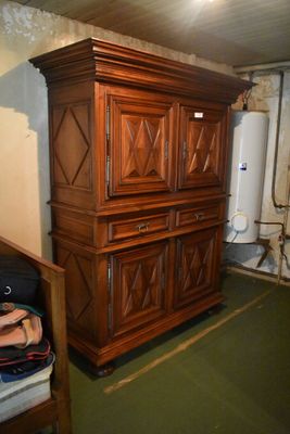 a wooden cabinet in the corner of a room with a suitcase on the floor