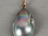a close up of a black pearl pendant on a white surface