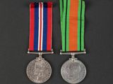 two medals with ribbons and a coin on a black background