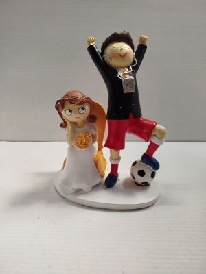 une figurine représentant un couple de mariés avec un ballon de football