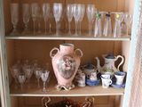 many glasses and vases on the shelves in this cabinet