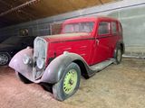 une vieille voiture rouge garée dans un garage à côté d'une voiture noire