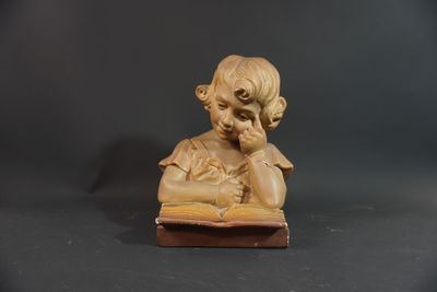 statue of a young boy reading a book on a black background