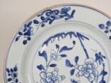 a blue and white plate with flowers and birds on it