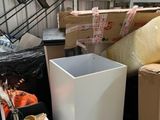 a white trash can sitting next to a pile of boxes