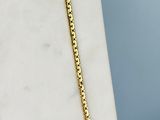 a close up of a gold chain necklace on a marble surface