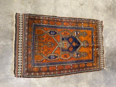 an orange and blue rug laying on top of a cement floor