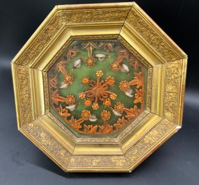 une assiette richement décorée, dorée et verte, ornée d'oiseaux et de fleurs