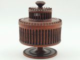 un petit gâteau en bois posé sur un socle, sur fond blanc