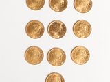 several gold coins are arranged in a triangle on a white surface