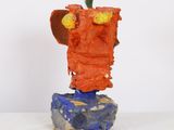 a sculpture of a face made out of clay on top of a rock