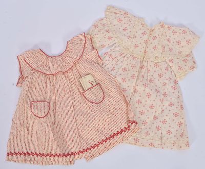 Deux vêtements pour bébé sont présentés sur une surface blanche