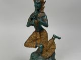 bronze statue of a person sitting on a rock with a bird in his hand