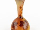 a glass vase with leaves on it on a white surface