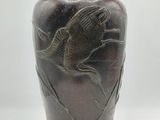 a brown vase with a bird on it on a white surface