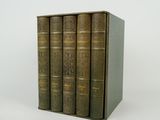 quatre vieux livres sont empilés les uns sur les autres sur une surface blanche