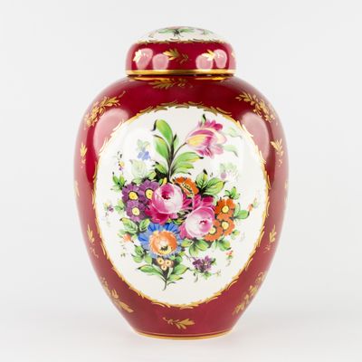 un vase rouge orné de fleurs peintes sur fond blanc