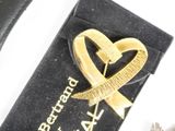 a gold heart brooch with a ribbon on top of it