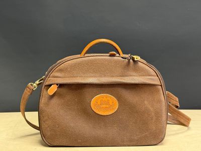 a small brown bag with a leather handle on a wooden table