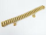 gros plan d'un bracelet en or sur une surface blanche