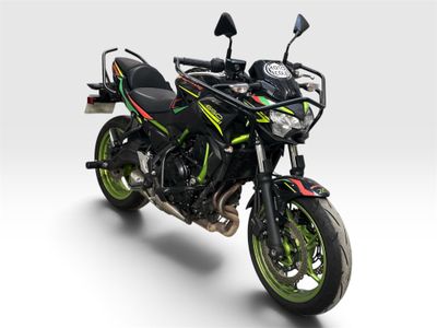 une moto noire et verte garée sur une surface blanche