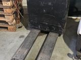 a fork lift truck parked in a garage next to a stack of pallets