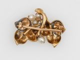 an image of a gold brooch with pearls and leaves