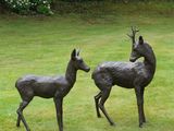 two statues of deer standing in a grassy field