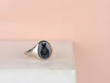 un gros plan d'une bague-sceau en argent sur laquelle est apposé un cachet de cire noire