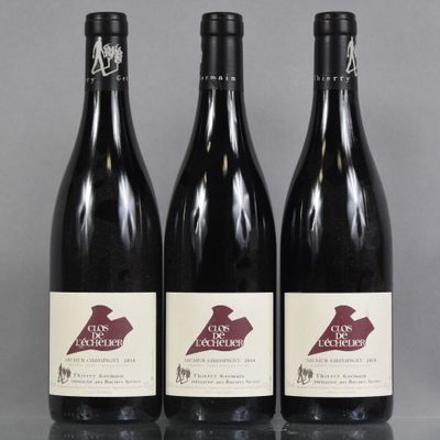 three bottles of red wine are lined up on a table