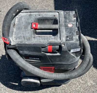un aspirateur posé par terre, muni d'un tuyau