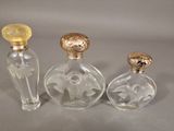 three small glass bottles with gold lids and a gold stopper