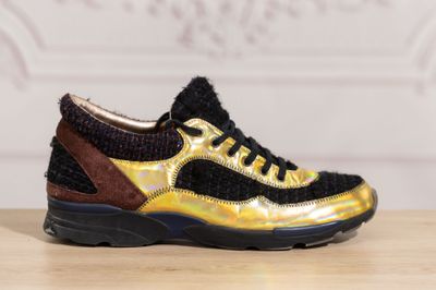 the black and gold sneakers are sitting on a wooden table