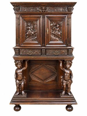 une armoire ancienne en bois ornée de figures sculptées sur le dessus
