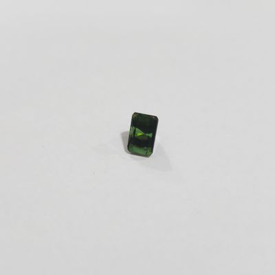 a green tourmaline stone on a white surface