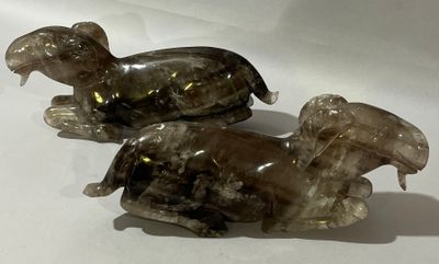 deux figurines en verre représentant des éléphants assis sur une surface blanche