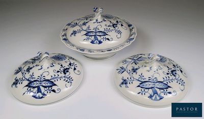 Trois plats bleus et blancs avec leurs couvercles sont posés sur une table