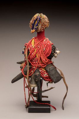 une image représentant une sculpture d'une femme vêtue d'une robe rouge et portant une coiffe