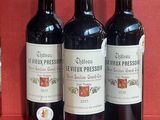 Trois bouteilles de vin rouge sont alignées sur un comptoir rouge