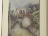 framed painting of a street with buildings and trees in the background