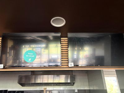 deux téléviseurs accrochés au mur au-dessus du plan de travail de la cuisine