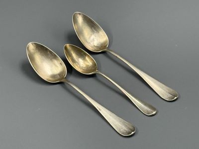 quatre cuillères en argent sont alignées sur une surface grise