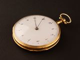 a gold pocket watch sitting on a black surface