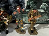 three figurines of soldiers standing in front of a sign